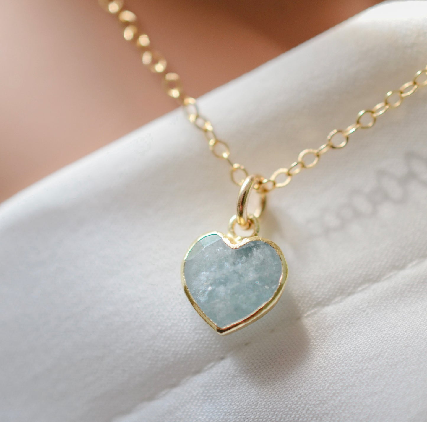 Pale blue natural aquamarine gemstone heart pendant set on a 14k gold filled chain. The stone is genuine and faceted with a 22k gold electroplate bezel.