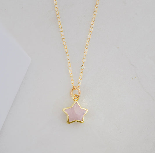 Dainty rose quartz star pendant necklace on a gold chain.