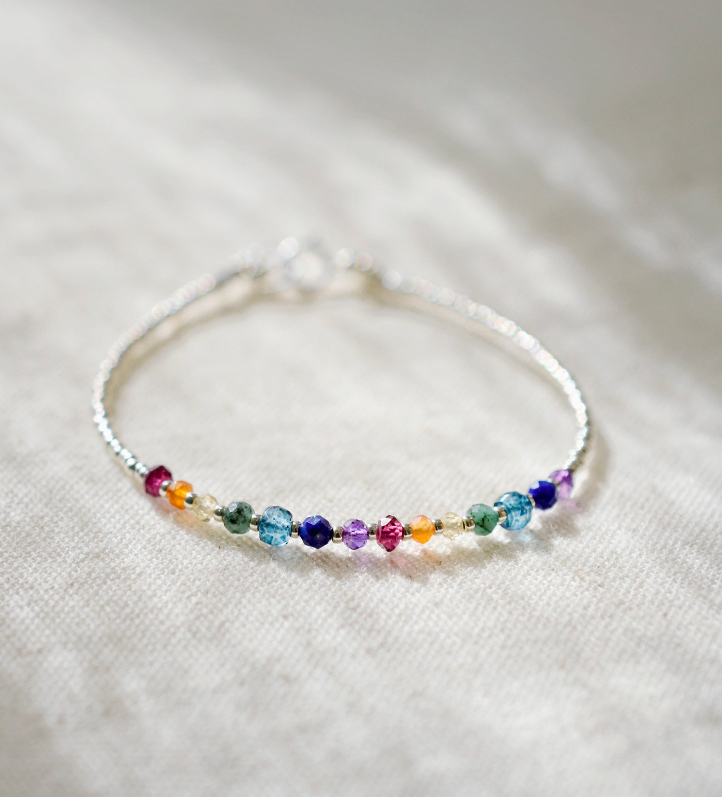 this dainty minimalist bracelet is handmade in Connecticut with natural crystal gemstones in order of the chakras. The stones are arranged like a rainbow.
