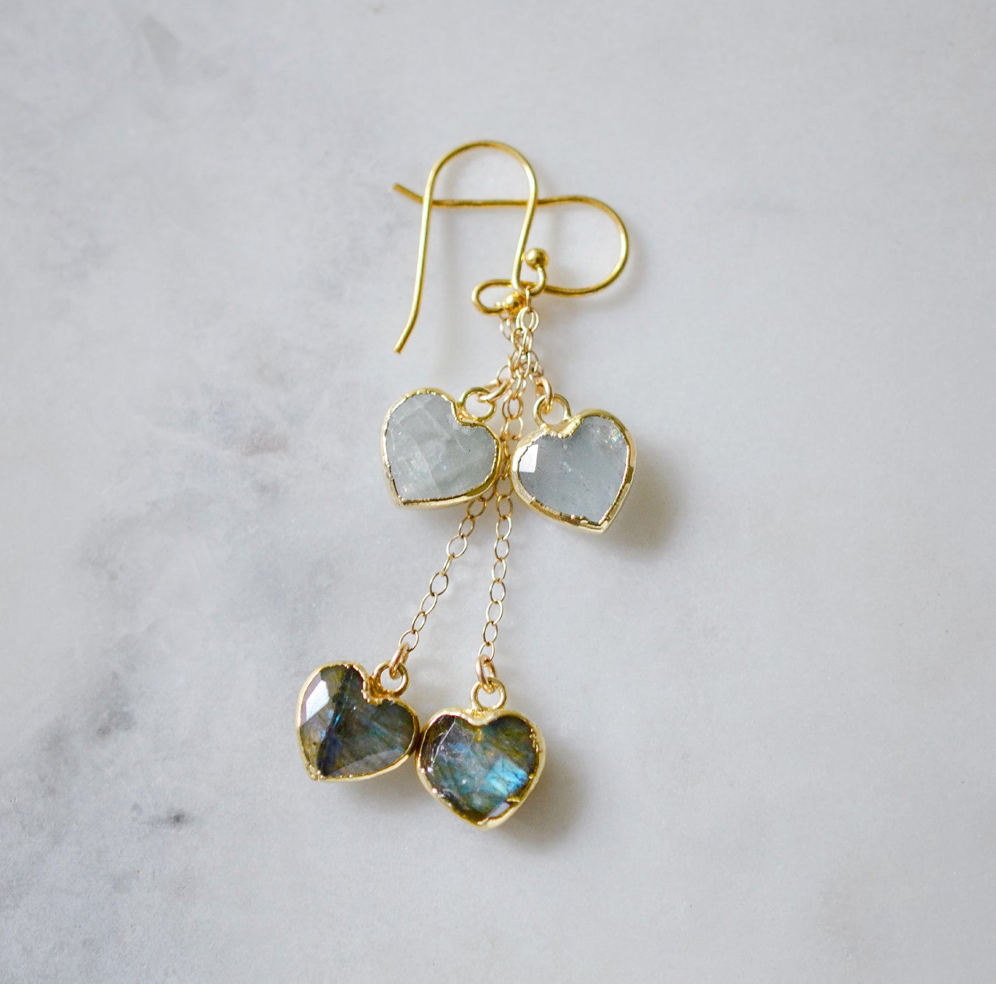 14k gold filled handmade earrings with heart-shaped gemstones on a light gray background. The stones are aquamarine and labradorite.