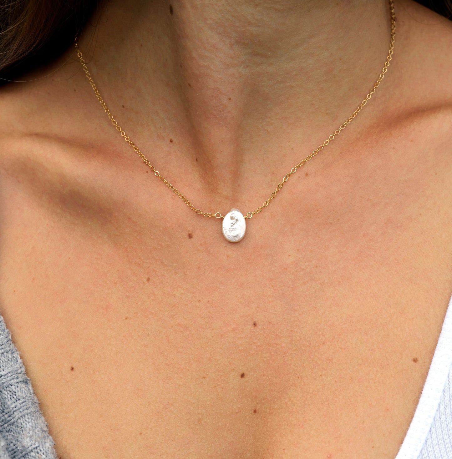modeled image. A dainty flat, oval-shaped white freshwater pearl is set within a 14k gold filled or sterling silver chain. Both styles are shown.