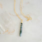 Long green, white, and clear real natural moss agate stone set on a 14k gold filled chain. The pendant is a long thin oval shape.