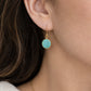 A close-up of a woman's ear wearing a gold dangle earring with a round turquoise-blue stone. Handmade with natural smooth polished turquoise by Gemnia in Connecticut. 