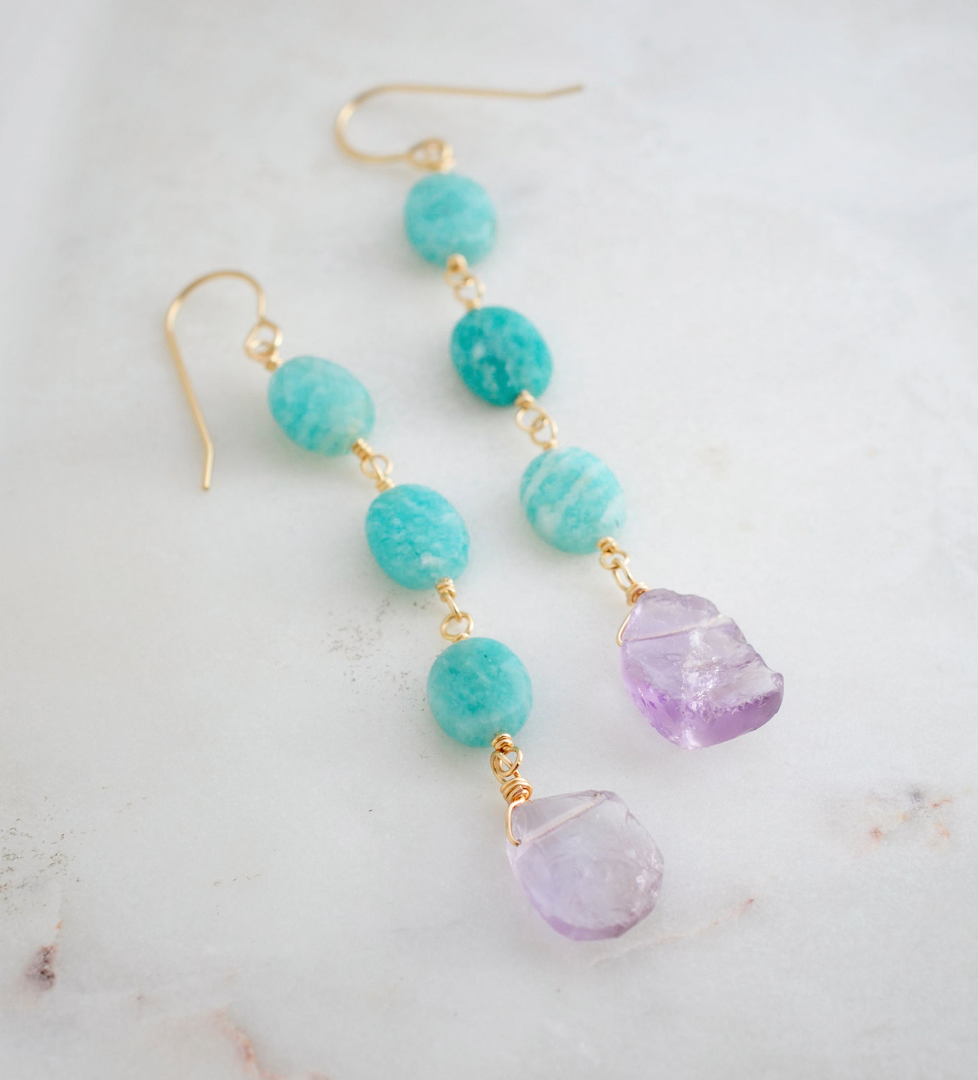 Three Amazonite faceted oval stones hang over raw, pale purple Amethyst crystals. Shown in the 14k gold filled style.