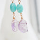 Three Amazonite faceted oval stones hang over raw, pale purple Amethyst crystals. Shown in the 14k gold filled style. Close up image.