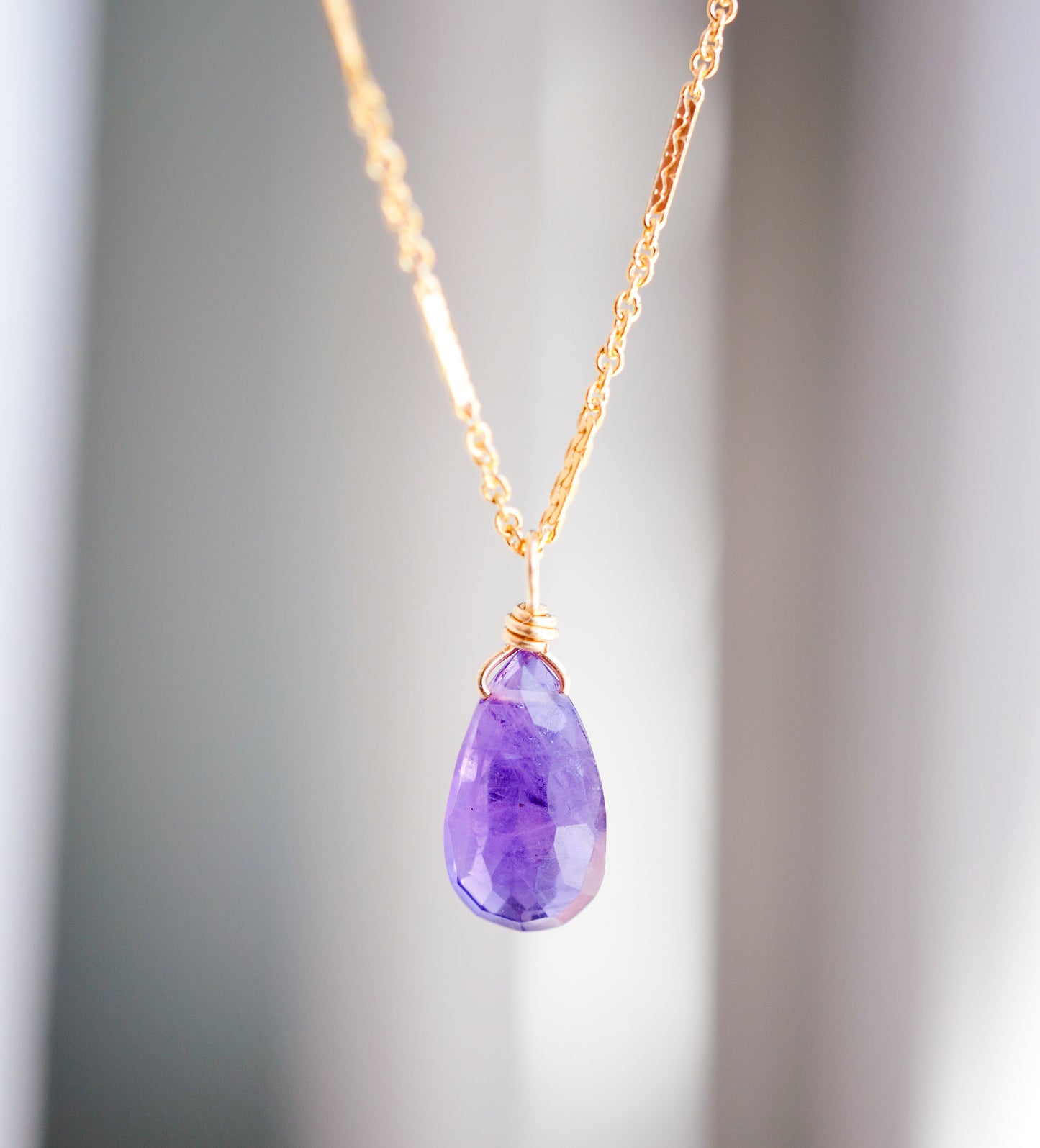 Close up of natural purple Amethyst teardrop pendant set onto a gold filled "glimmer" chain.