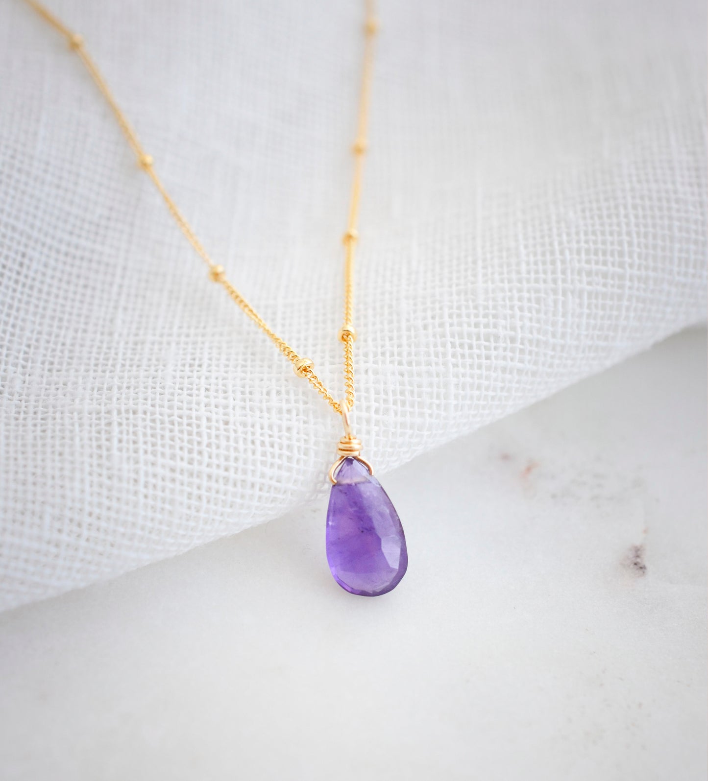 Dainty purple Amethyst teardrop crystal set onto the 14k gold filled droplet chain.