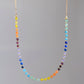 Rainbow chakra gemstone necklace. Crystals are beaded together in this pattern: yellow, orange, red, purple, blue, aqua, green. The gold style is shown.