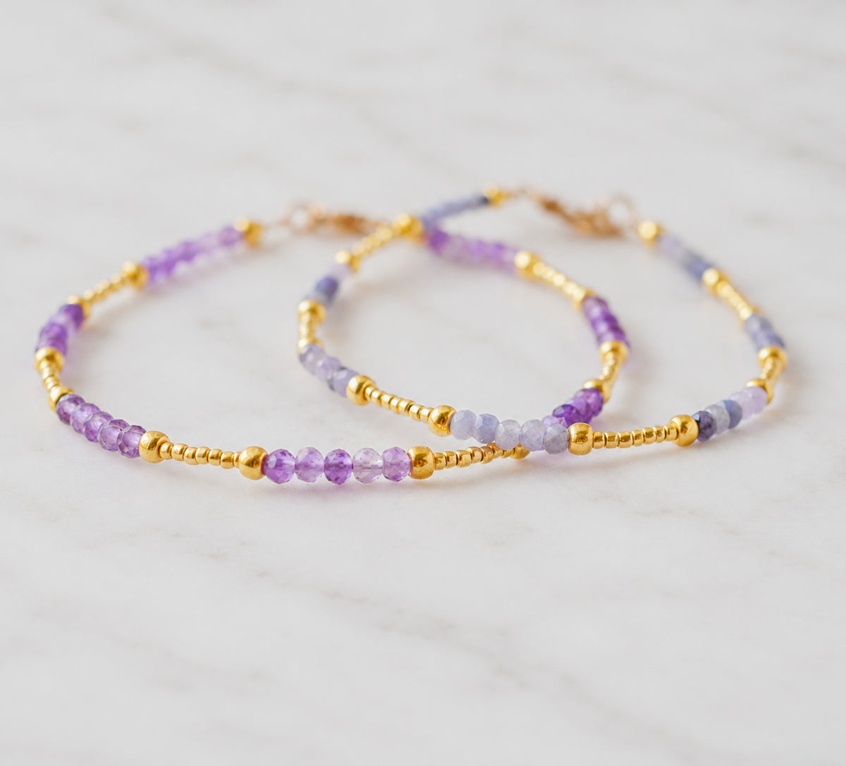 Two beaded bracelets with purple Amethyst and Tanzanite gemstone beads in gold. Handmade gemstone bracelets for layering and stacking.