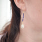 Natural blue lapis lazuli gemstone and white freshwater pearl long dangle earrings. The dangles are long and thin with oval freshwater pearls at the end. They come in 14k gold filled and sterling silver and a great gift for mom, girlfriend, anniversary, or yourself. Modeled image.