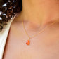 Natural orange triangular shaped Carnelian gemstone set onto a gold chain. Modeled image. 