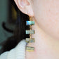 A person wearing long labradorite dangle earrings with gold and silver colors.