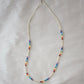 Tiny stones arranged in the order of the seven chakras or rainbow colors. Colors include: purple, blue, aqua, green, yellow, orange, and red. Close up of the silver style.
