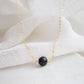 Close up image of a black Lava stone set onto a 14k gold filled chain. The stone is round with an irregular surface. 