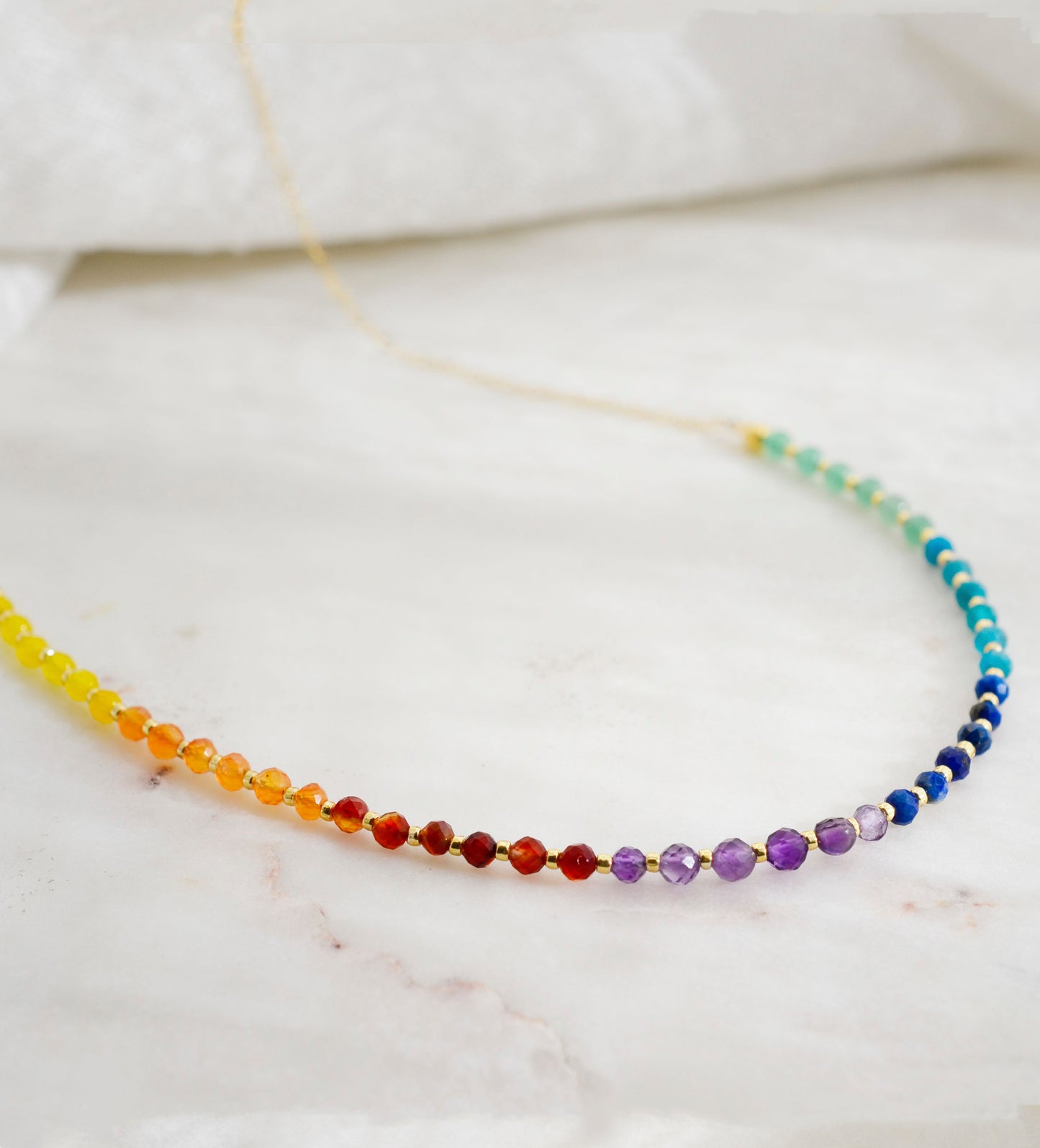 Close up of the gemstones in this beaded rainbow necklace made of natural crystal gemstones. The 14k gold filled style is shown. Handmade in New England by Gemnia.