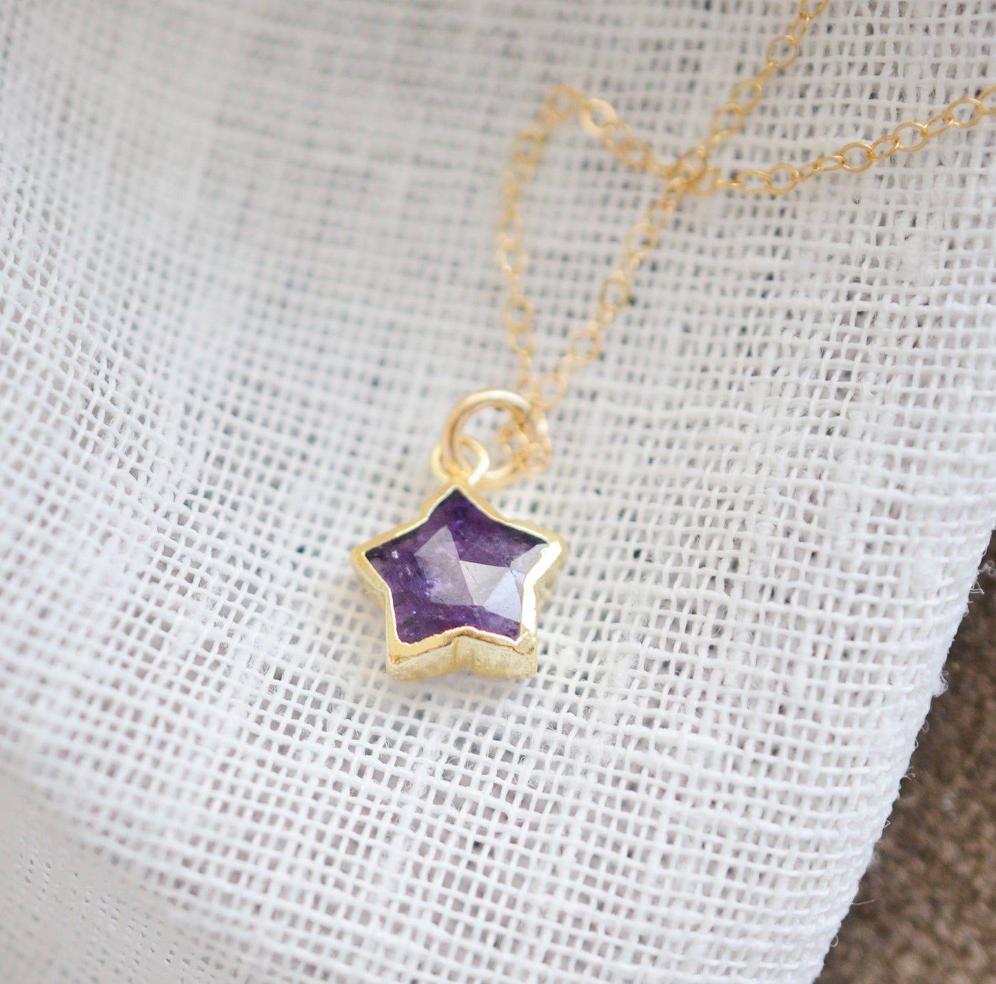 Handmade genuine purple amethyst star pendant set on a 14k gold filled chain. The stone is shown on its side. The bezel is only on the edges of the stone.