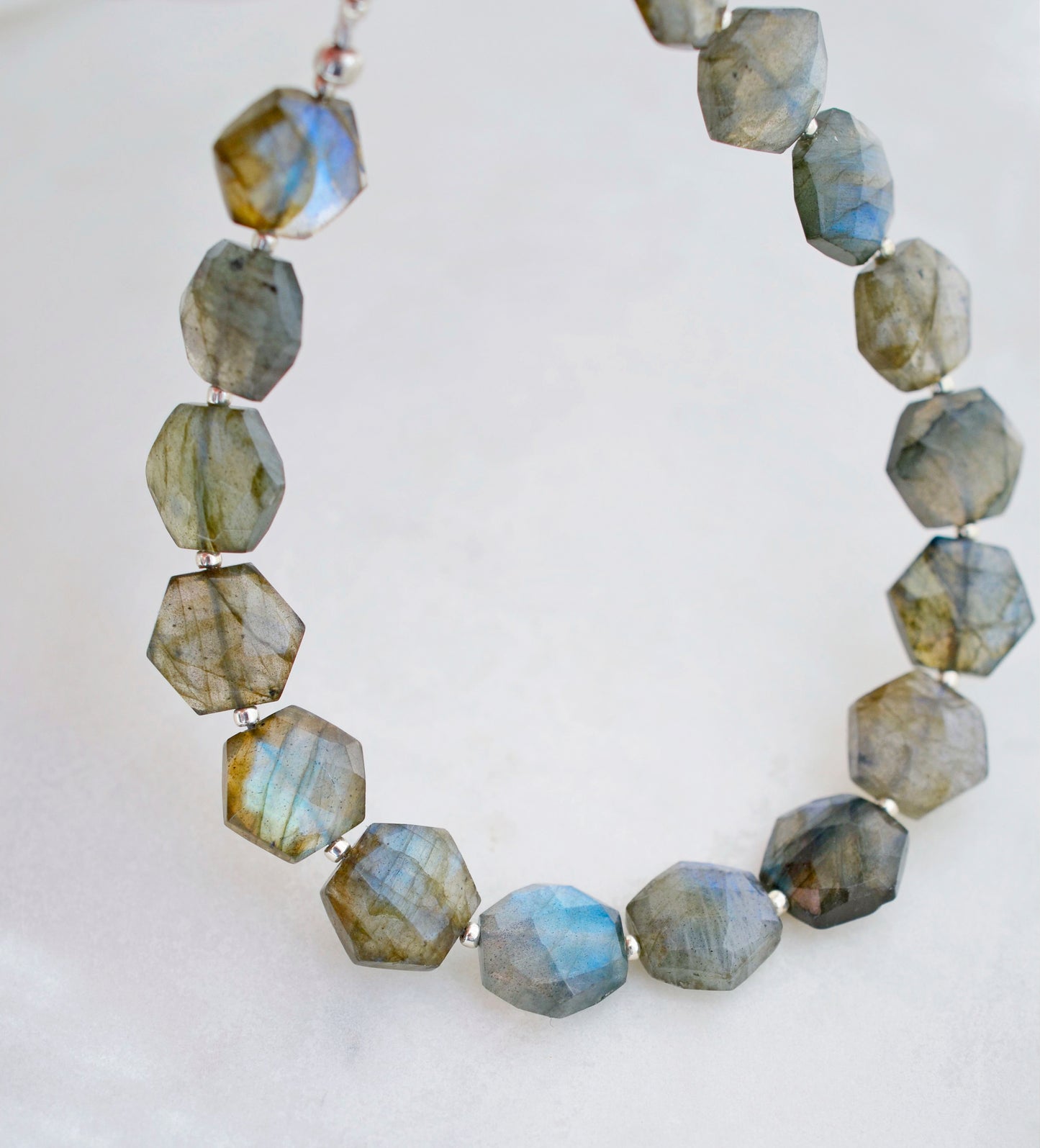 Close up of beaded Labradorite gemstone bracelet shown in sterling silver. The stones are faceted and cut in a hexagonal shape.