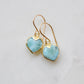 Aqua blue, natural Larimar stone heart earrings in gold. The stones range in blue, white, or green with the occasion mark of brown or black.