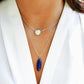 Close-up of a person wearing layered necklaces with a blue lapis lazuli pendant and white freshwater pearl necklace. Handmade jewelry in Connecticut.