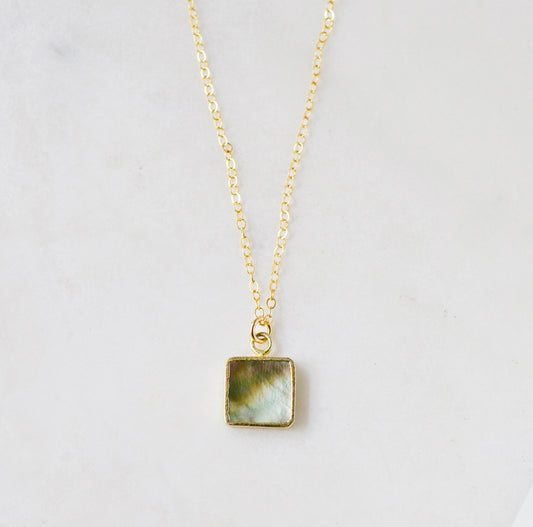 A natural silver colored mother of pearl square shaped pendant set on a 14k gold filled chain. This necklace is handmade in Connecticut by Gemnia.