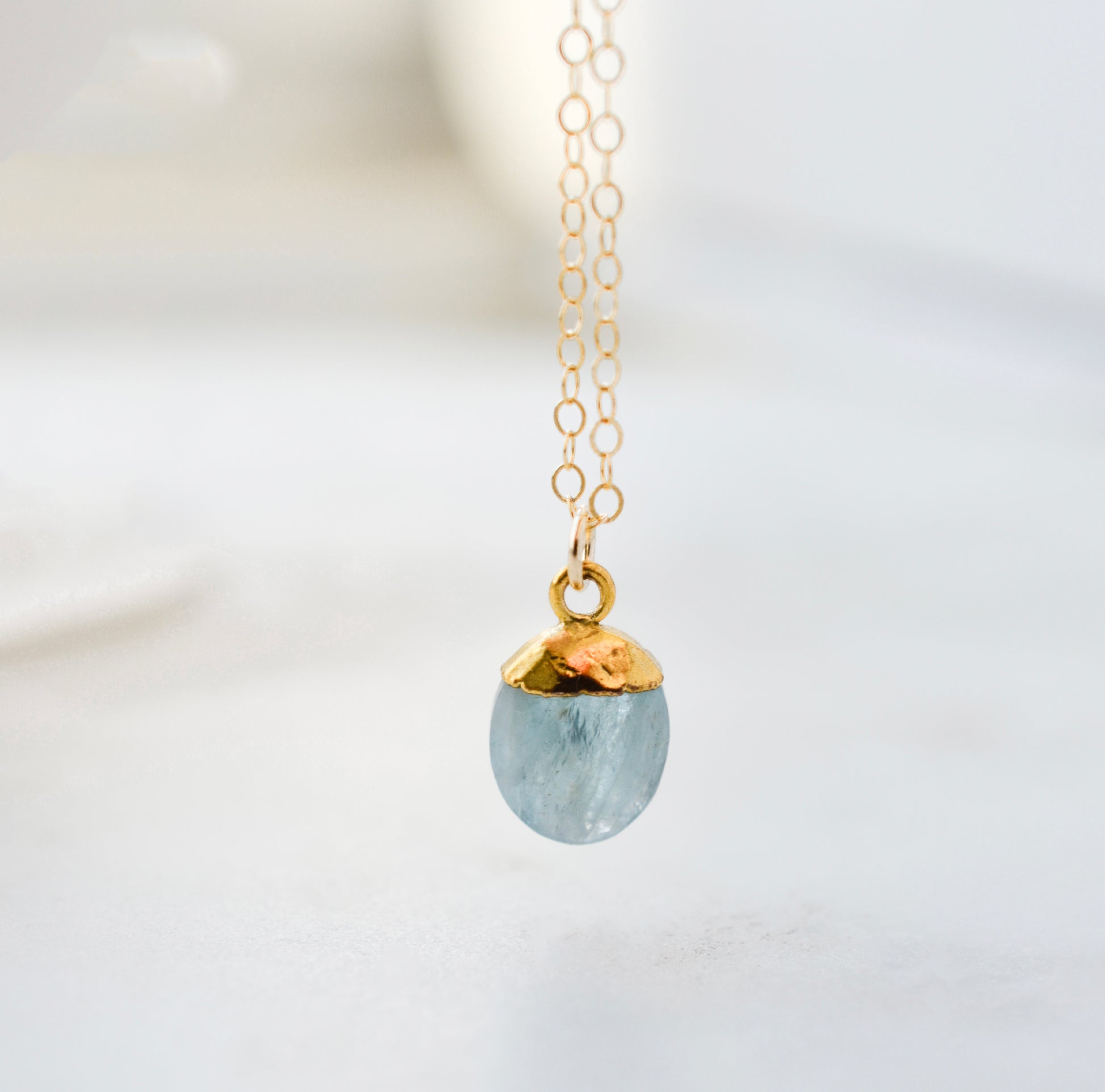 Stone pendant with a dainty aquamarine gemstone set on a 14k gold filled chain. The necklace is handmade in Connecticut by Gemnia Jewelry.