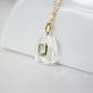 Side view. Handmade Maris necklace featuring a Blue Topaz set inside a clear Rock Crystal frame on a 14K Gold Filled chain. Ideal gift for wife, girlfriend, or mom. Minimalist topaz pendant for layering.