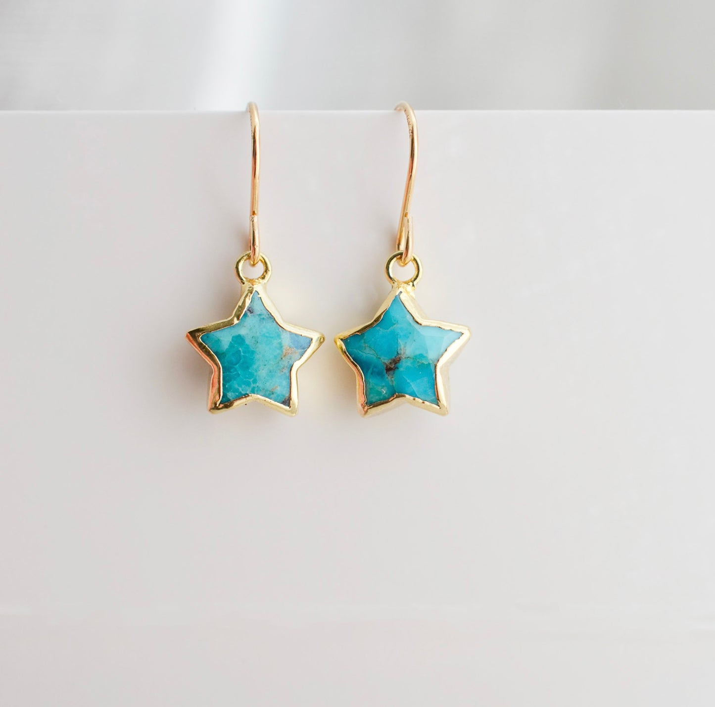 Celestial star earrings with turquoise stones set in gold. These dainty minimalist gemstone earrings are handmade by Gemnia Jewelry in Connecticut.