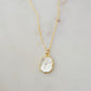 A smooth polished natural, white mother of pearl slice has been set in a 24k gold electroplated bezel and suspended from a 14k gold filled chain. The shell shimmers in shades of white, silver, and pink.
