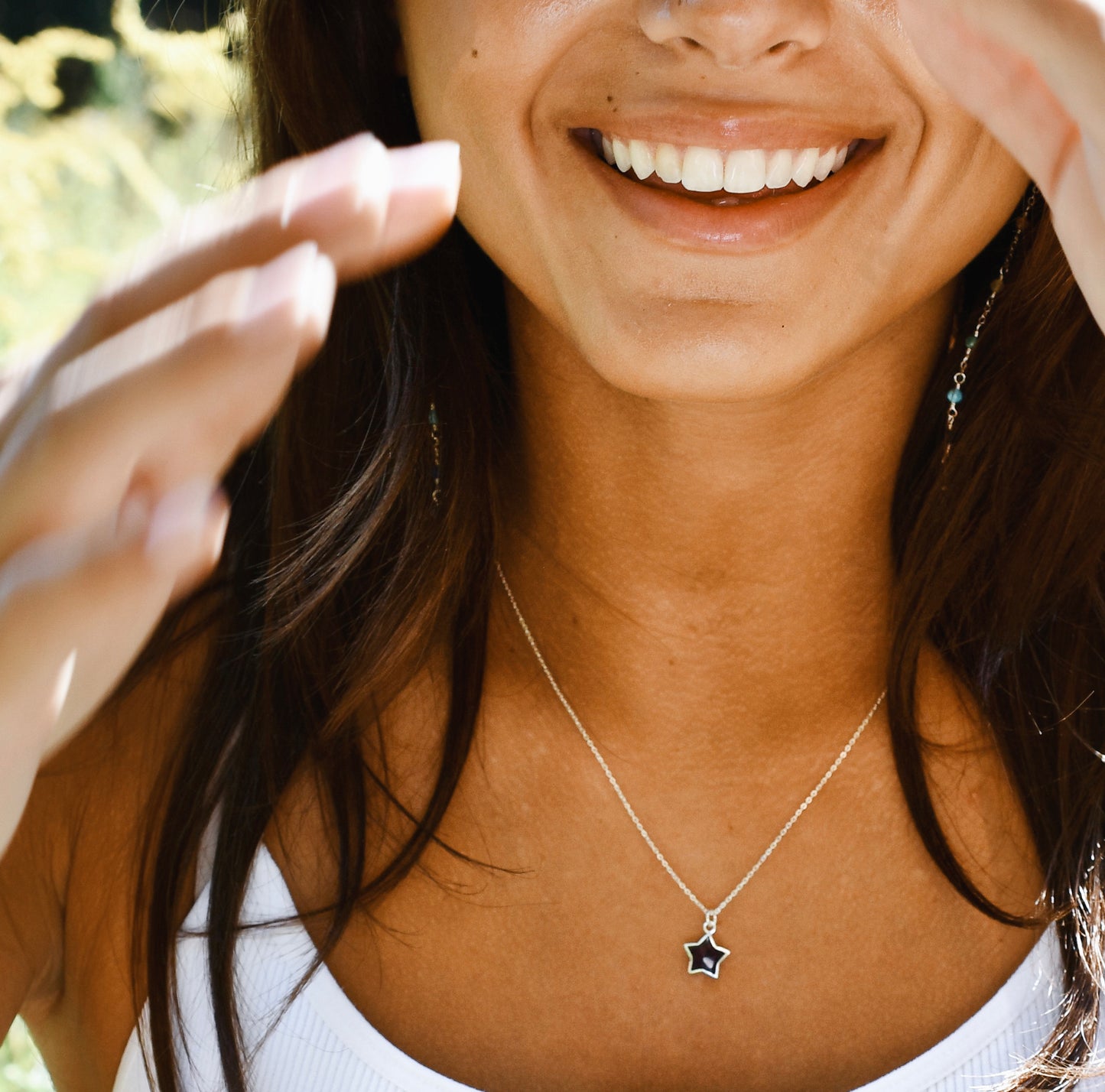 Woman wearing a necklace with a star pendant, outdoors. Modeled in sterling silver.