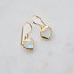 Natural rainbow moonstone stone heart earrings in gold. The stones are white, but flash blue with movement.