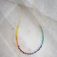 The single rainbow style beaded necklace is shown in gold.