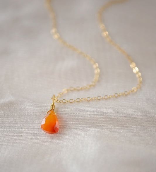 Natural orange triangular shaped Carnelian gemstone set onto a gold chain. Stones vary in color from orange to red.