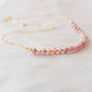 Natural pink Rhodochrosite beaded handmade necklace shown in 14k gold filled. The image is a size view showing the dainty metal beads. The gemstones vary in shades of pink, peach, white, and gray and are faceted rondelle shape. They span approximately 4 inches across the front of the necklace, then attach to a dainty cable chain. Also available in sterling silver.