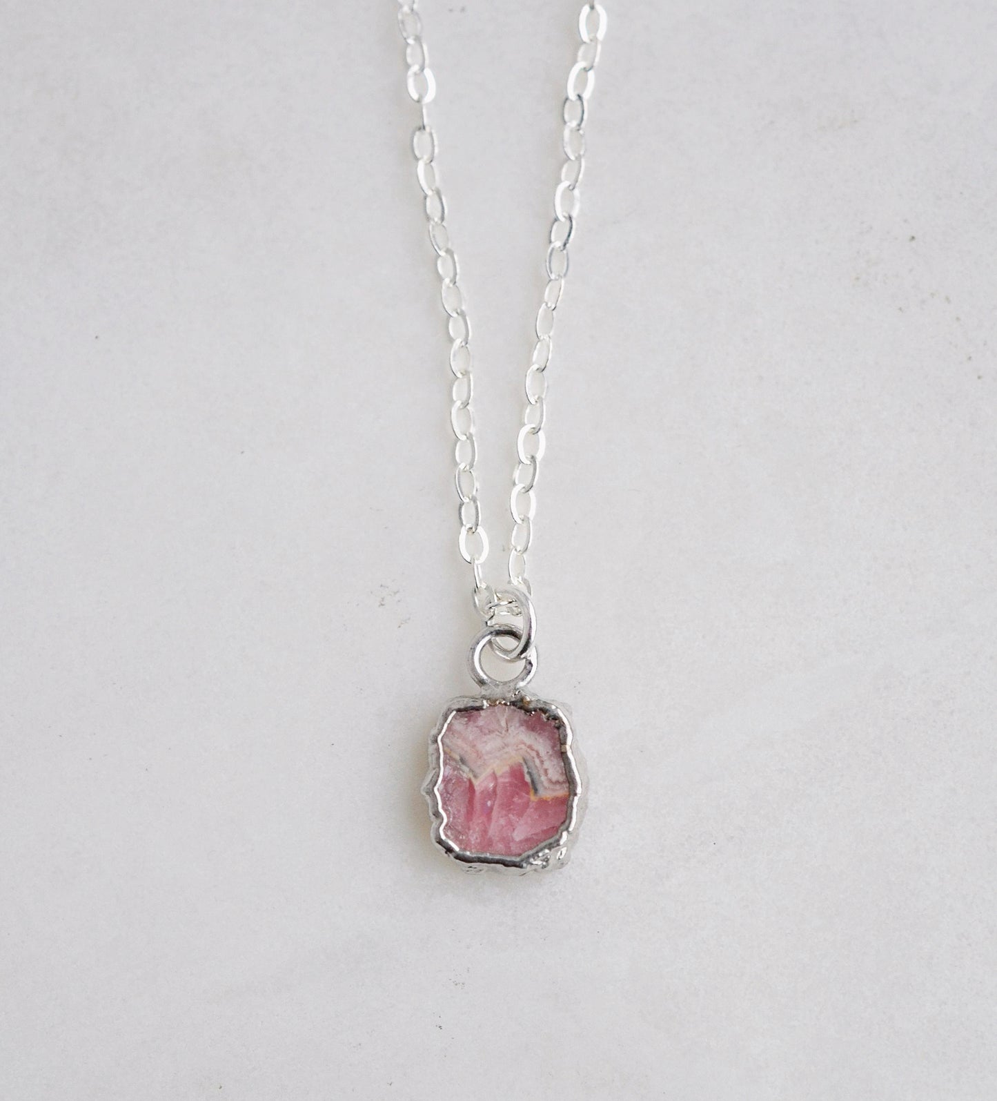 Natural pink Rhodochrosite sliced gemstone bezeled in sterling silver and set on a sterling chain.