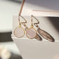 Natural pale pink rose quartz dangle earrings in a circle coin shape. The stones are smooth polished and are dainty, lightweight, and minimalist. 