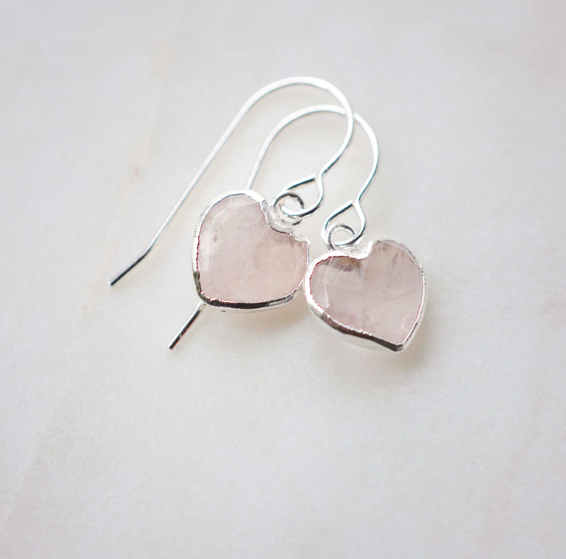 Dainty, handcrafted rose quartz heart earrings featuring a faceted, sparkling heart—the stone of universal love. These gentle dangles, approximately 0.5 inches (12mm/1.2cm) in size, are shown in sterling silver and are also available in 14k gold filled. They make a sweet and thoughtful gift for someone special. 