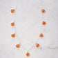 Multiple orange carnelian crystal gemstones dangle off a sterling silver chain.