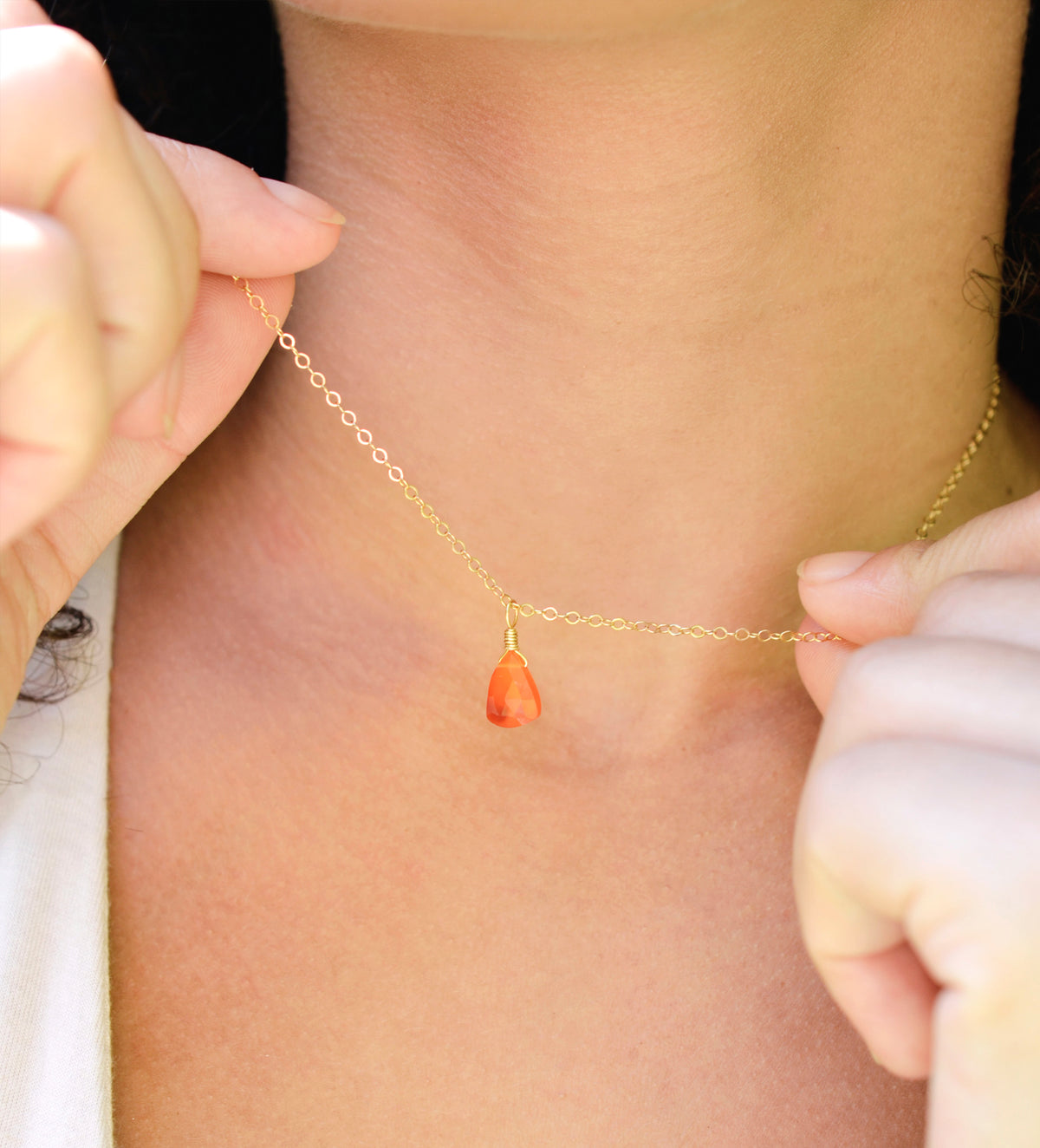 Natural orange triangular shaped Carnelian gemstone set onto a gold chain. Modeled image. 