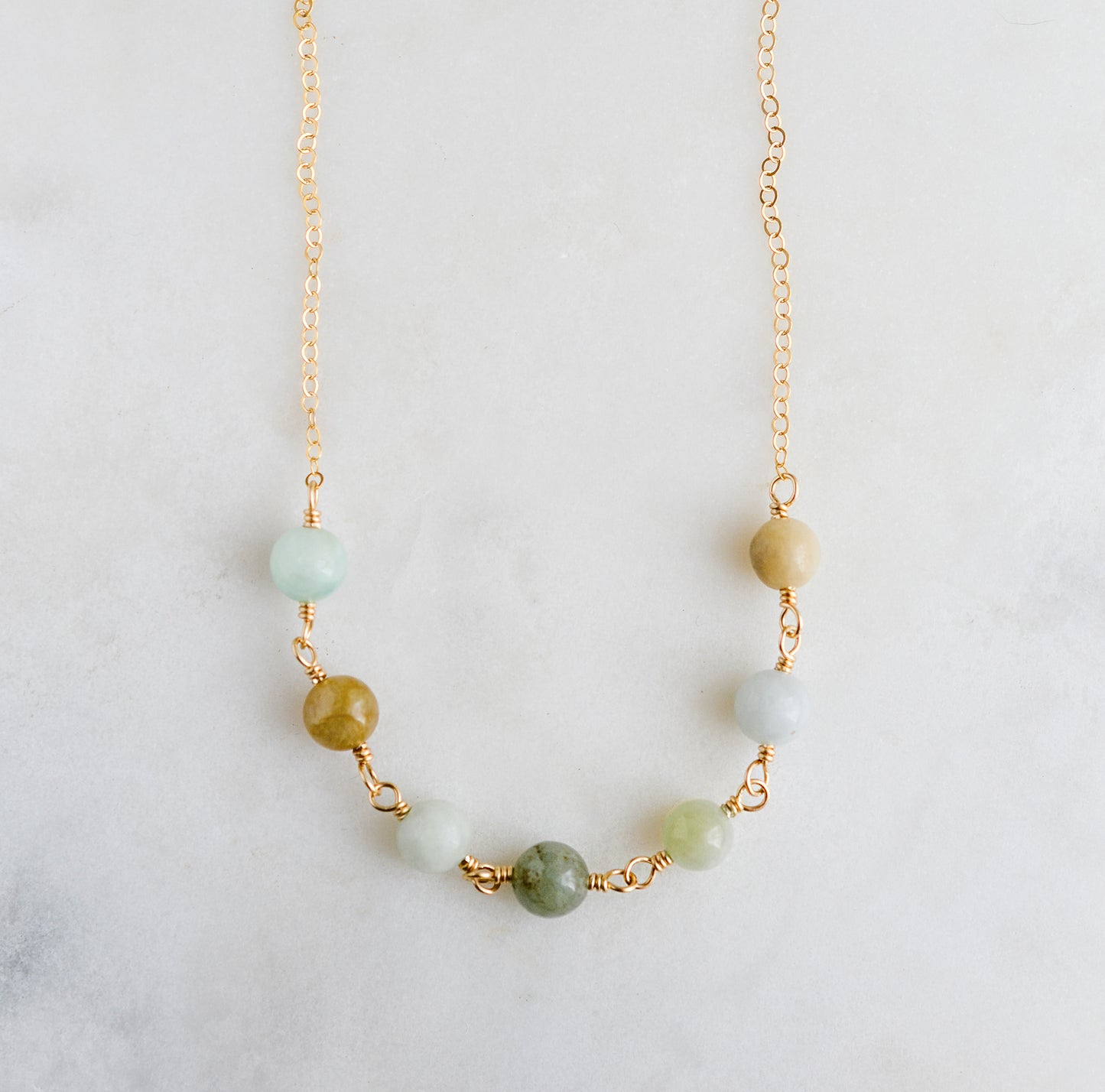 A multi-color natural real jade necklace featuring seven round green, brown, yellow, or blue natural stones. Handmade in Connecticut by Gemnia Jewelry.