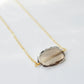 An irregular oval shape, smooth polished Smokey Quartz stone set onto a 14k gold filled chain. The stones edges are raw and irregular. 