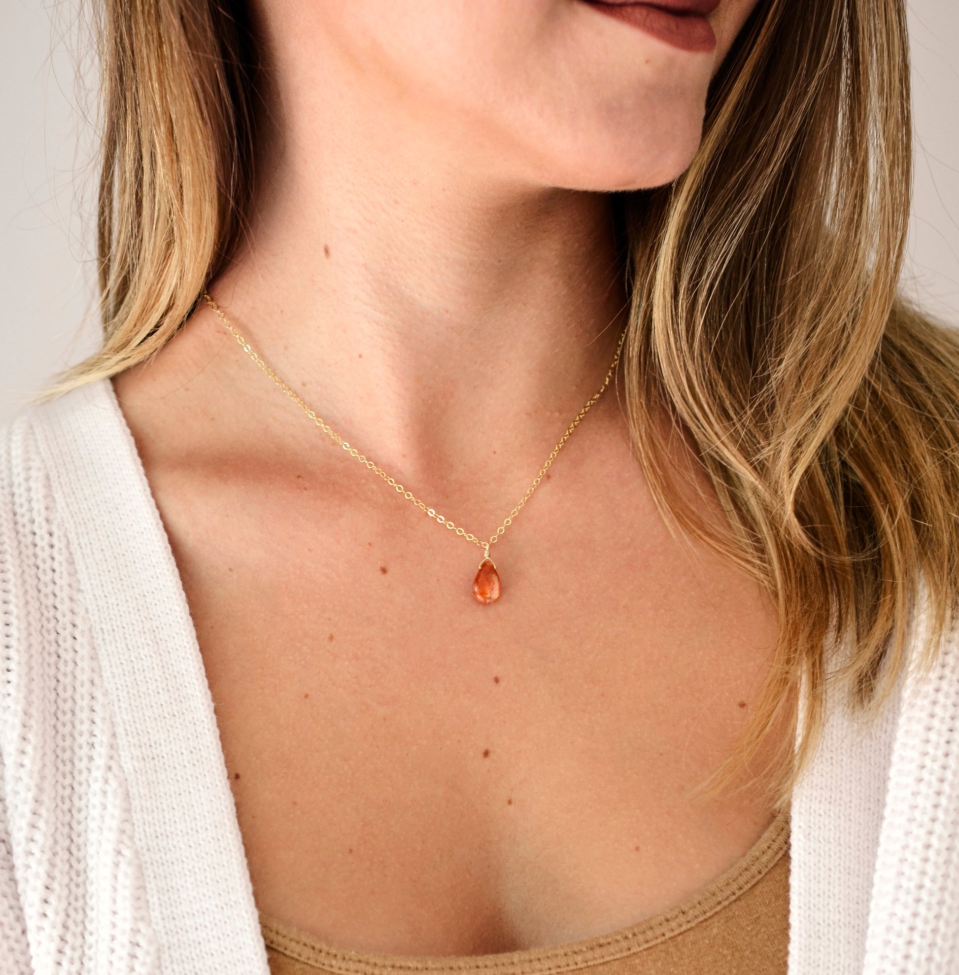 Orange Sunstone smooth polished teardrop pendant on a 14k gold filled chain. Modeled image. 16 inch chain.