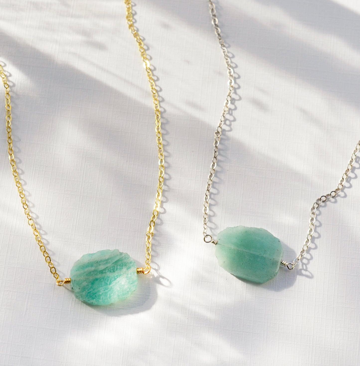 Aqua blue amazonite slice gemstone set onto a 14k gold filled chain. The stone is semi oval in shape, but irregular. It's smooth polished, but with raw edges. Both the silver and gold style are shown.