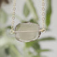 An irregular oval shape, smooth polished Smokey Quartz stone set onto a 14k gold filled chain. The stones edges are raw and irregular. Video.