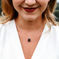 A modeled image of a woman wearing a rough, genuine, black tourmaline crystal necklace in sterling silver. The minimalist jewelry is handmade in Connecticut. 