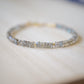 Blue flashing natural heishi or wheel shaped Labradorite gemstones strung together onto a bracelet. Tiny gold beads act as spacers between the stones. The gold style is shown.